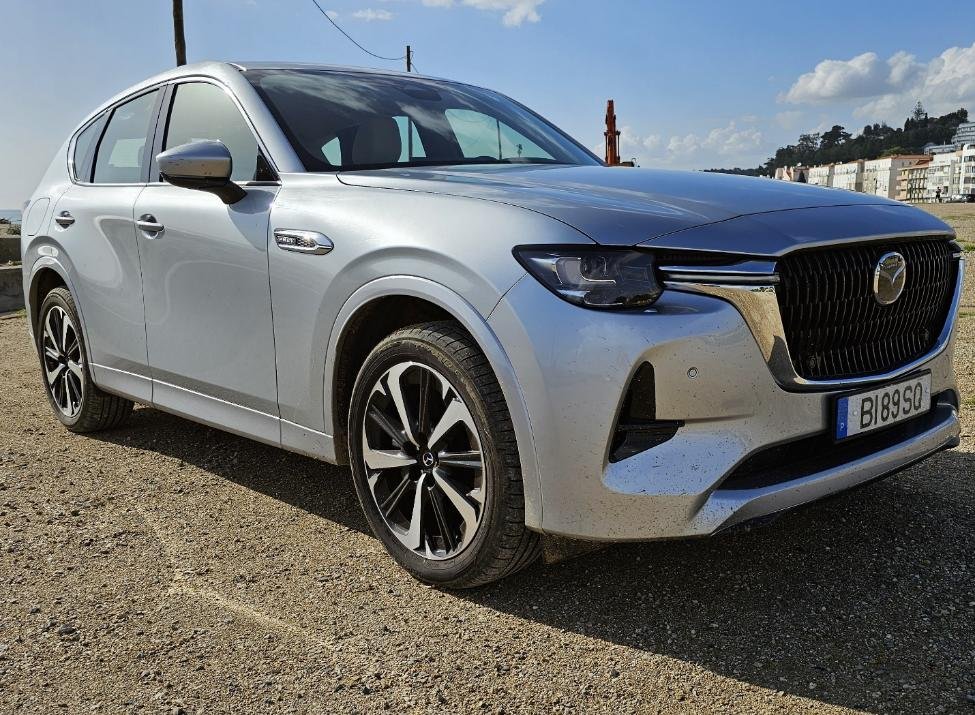 A silver car parked on gravel Description automatically generated