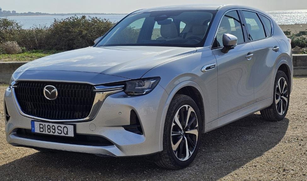 A silver car parked on gravel Description automatically generated